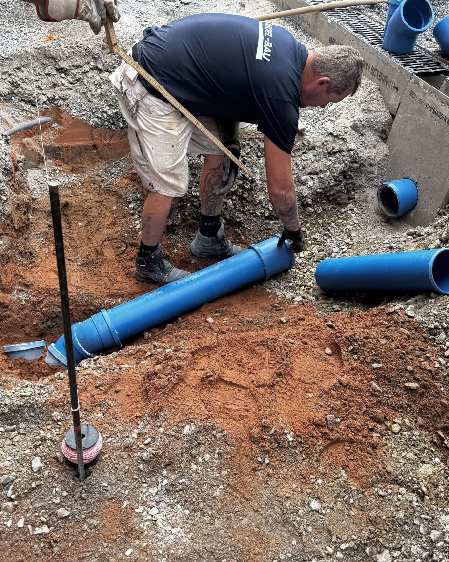 Person verlegt Rohre auf einer Baustelle